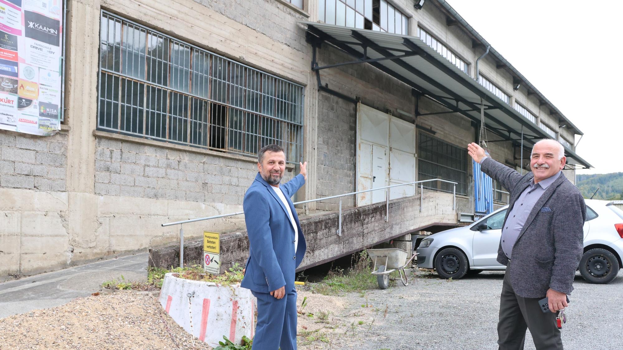 Zwei Männer zeigen auf ein altes Gebäude.