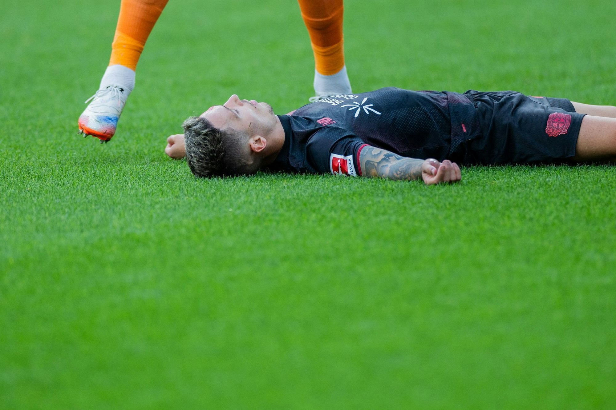 Bayer Leverkusens Kapitän Alejandro Grimaldo liegt nach einem Zusammenprall mit dem eigenen Mann benommen auf dem Boden.