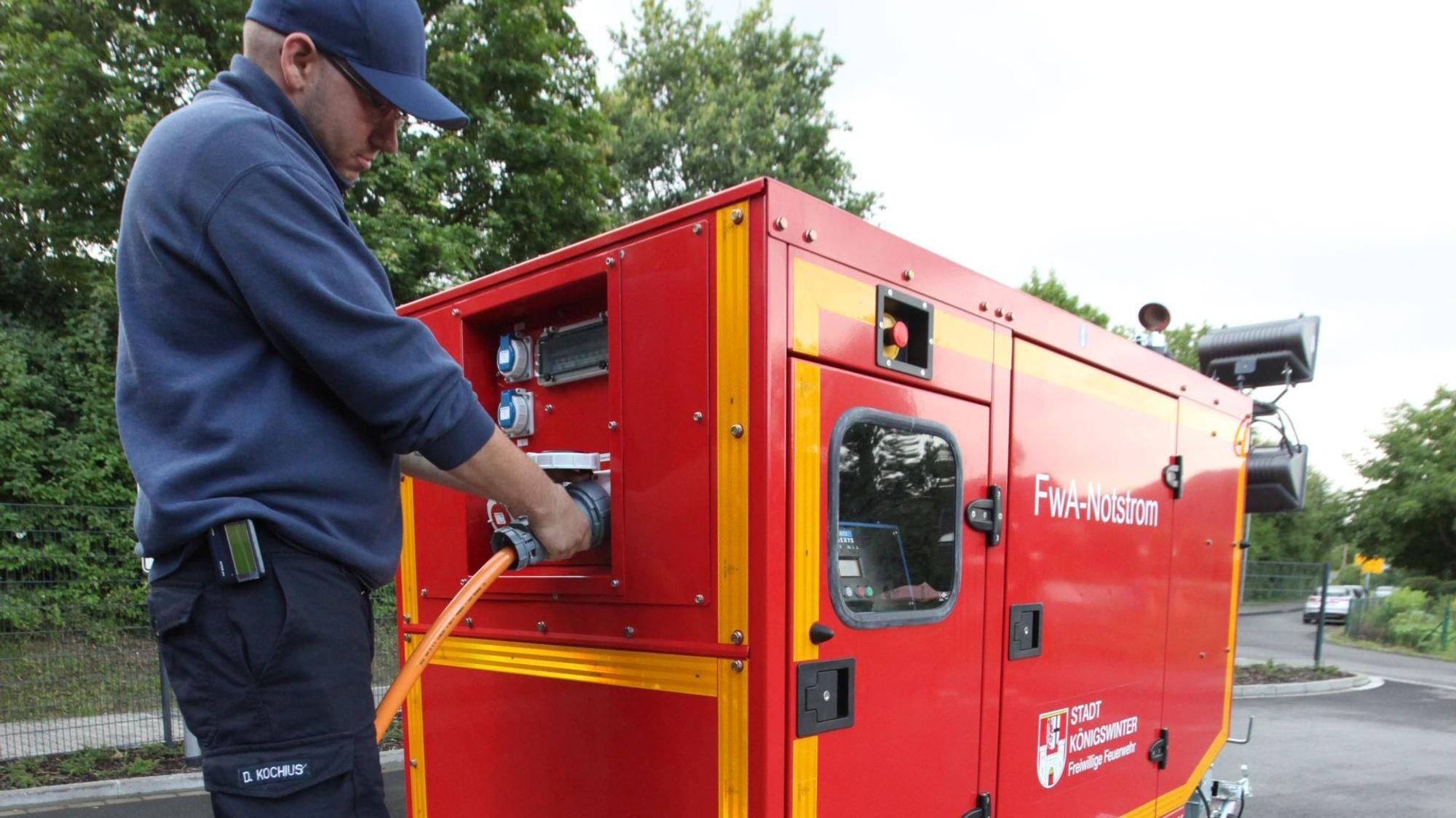 Ein Feuerwehrmann an einem roten Notstromaggregat.