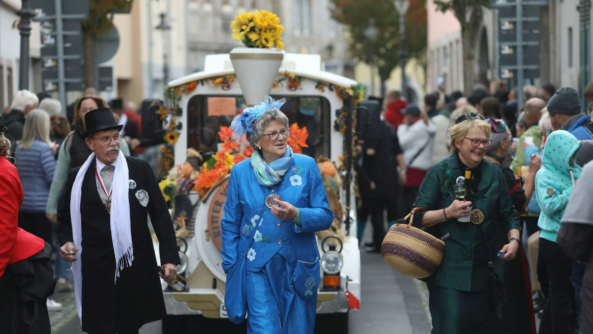 Ein Mann und zwei Frauen gehen vor einem Bähnchen durch die Altstadt.