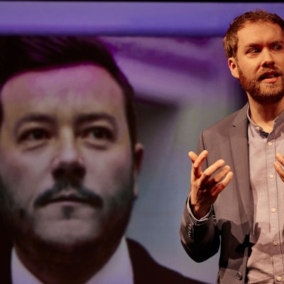 Calle Fuhr gestikuliert vor einem Bild von René Benko