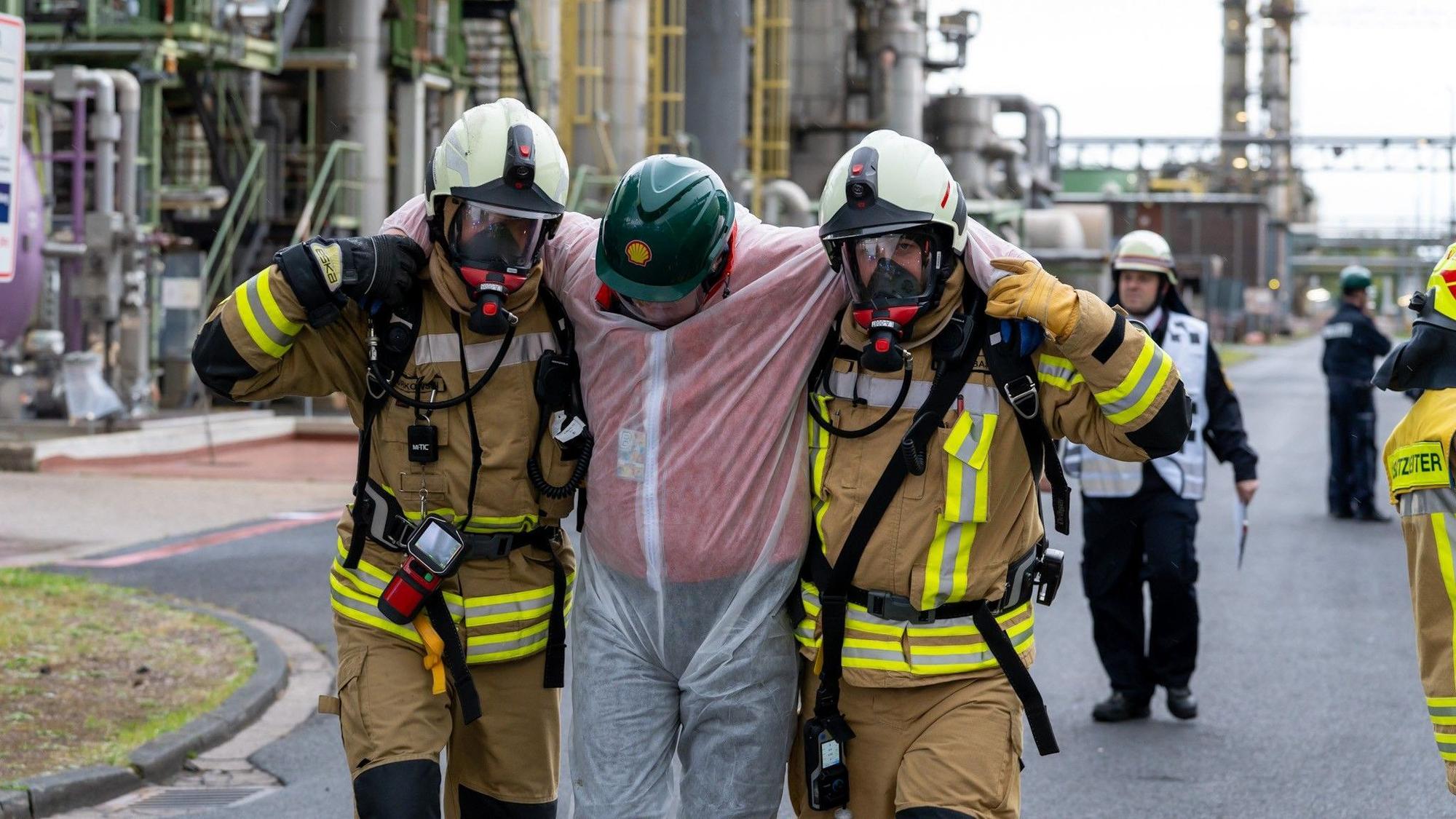 Zu sehen ist, wie zwei Feuerwehrleute bei einer Übung einen Verletzten tragen.