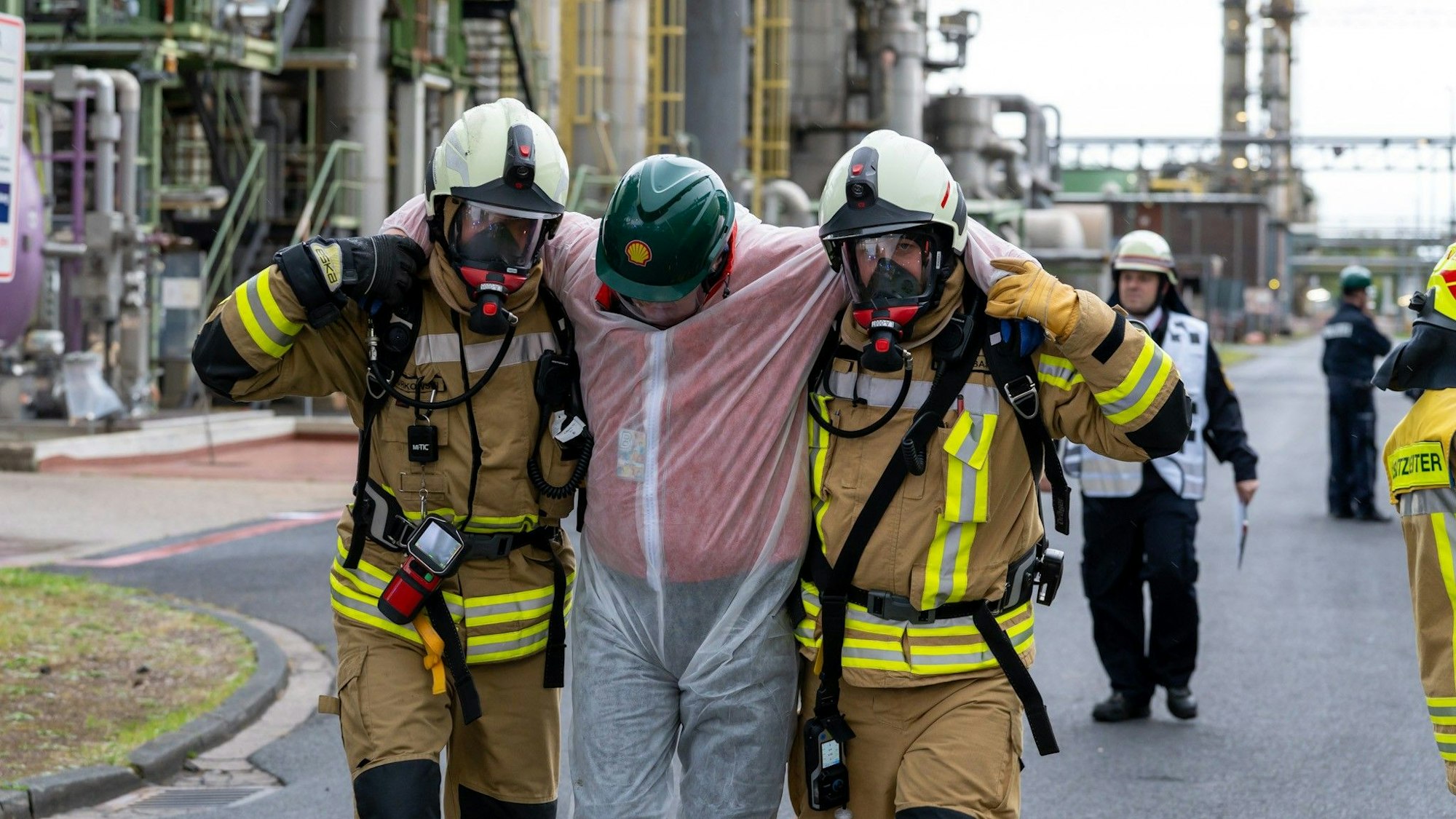 Zu sehen ist, wie zwei Feuerwehrleute bei einer Übung einen Verletzten tragen.