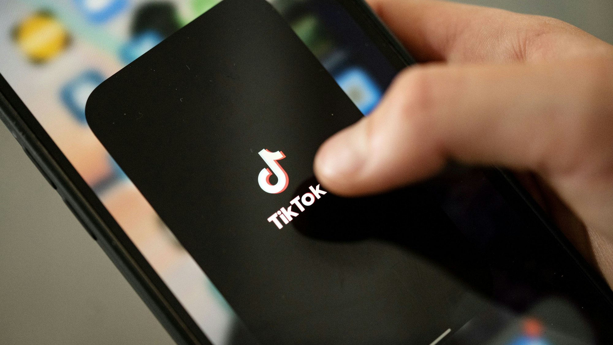 Ein Teenager tippt auf das Tiktok-Logo auf einem Smartphone.