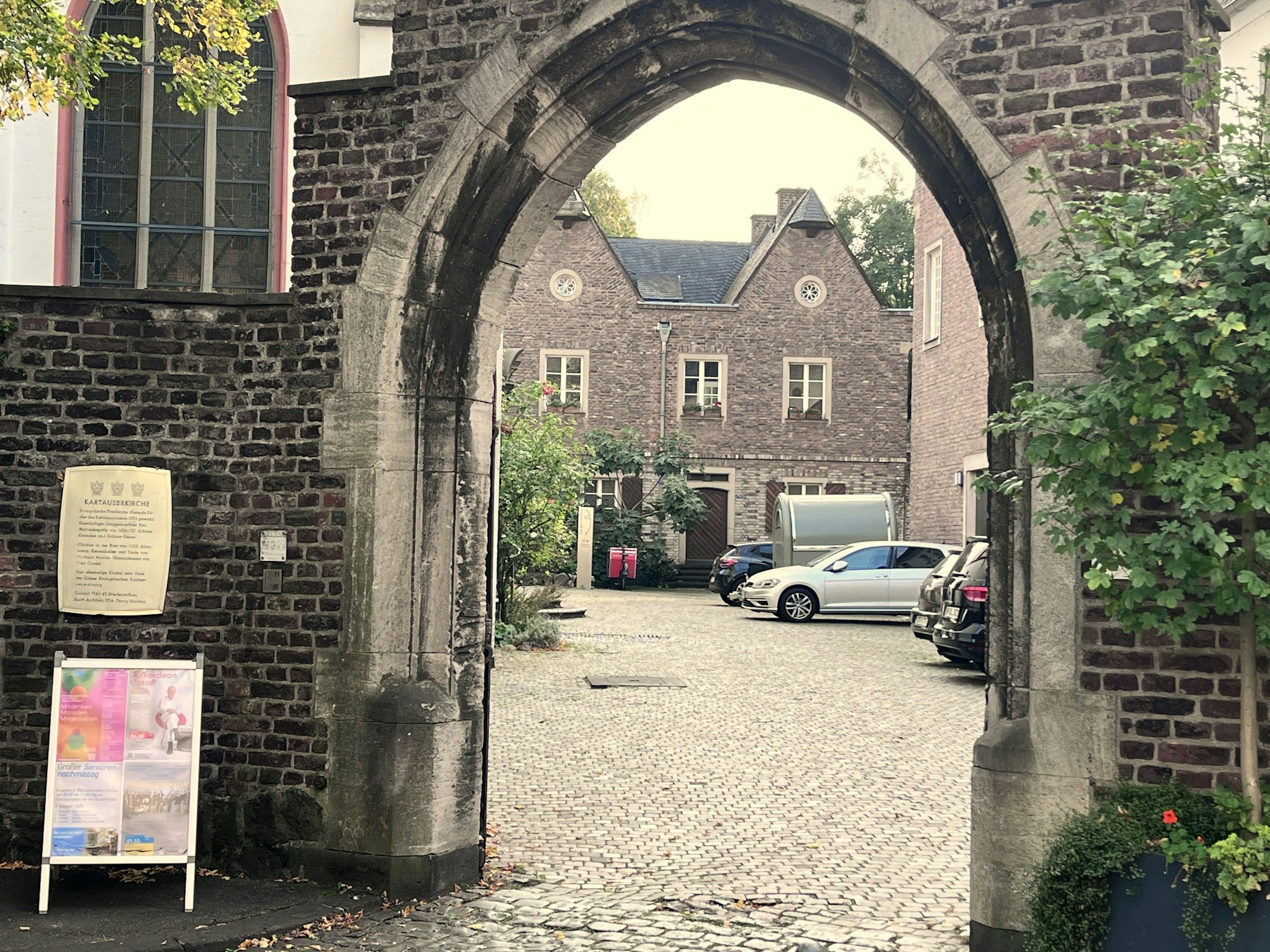 Blick durch einen Torbogen in einen Kopfstein-gepflasterten Innenhof mit weiteren alten Gebäuden.