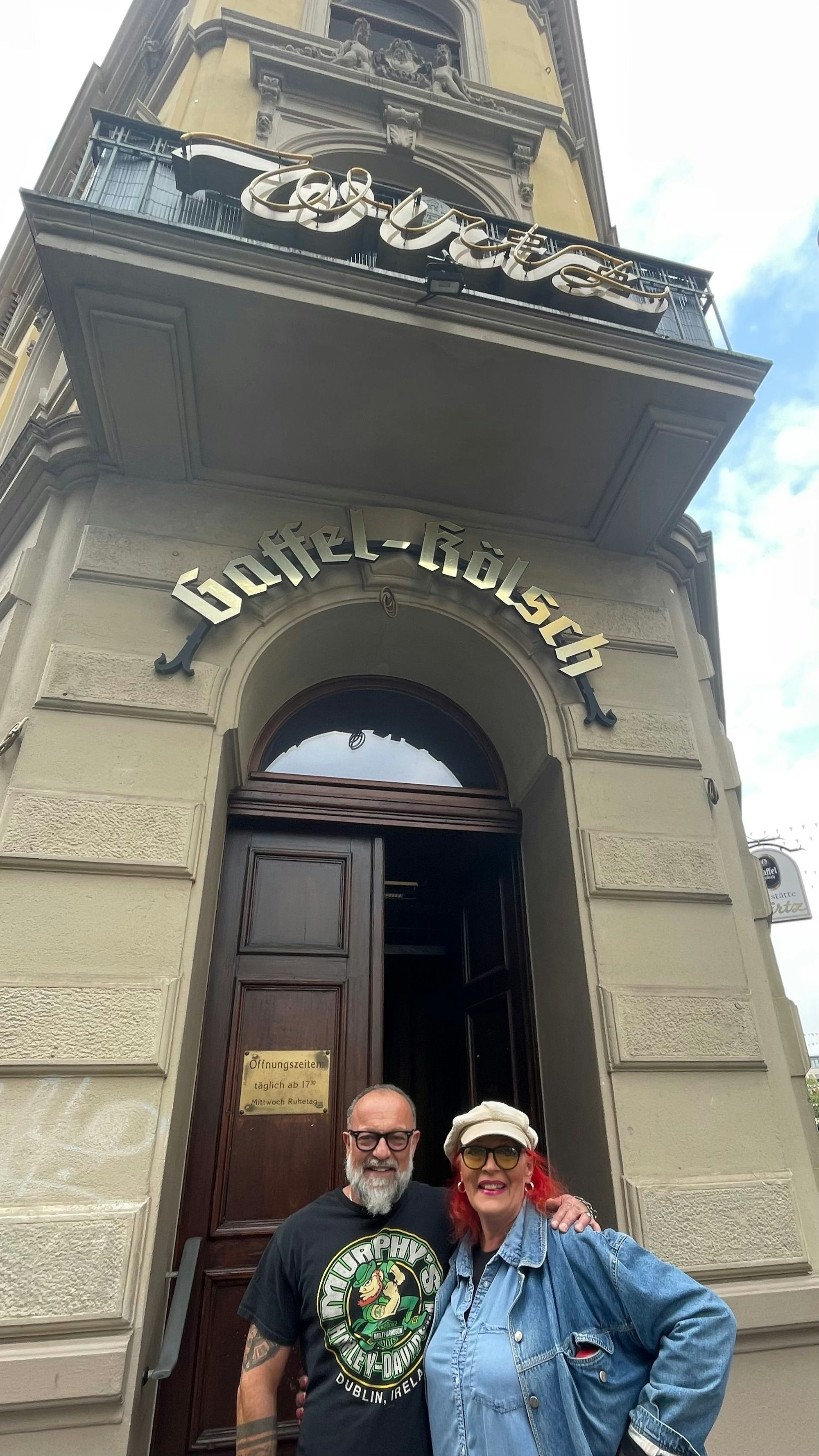 Ein Mann mit Bart und eine Frau mit Kappe und Jeansjacke stehen nebeneinander.
