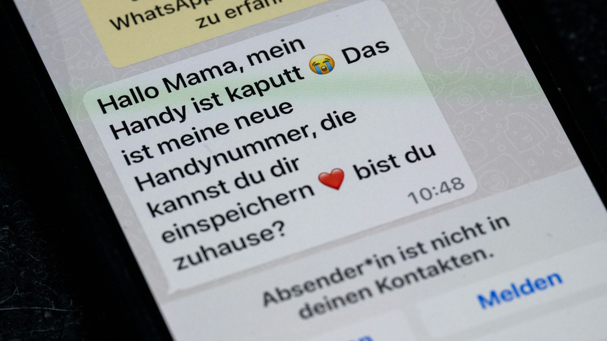 Ein Handy mit einer Betrüger-Nachricht per Whatsapp.