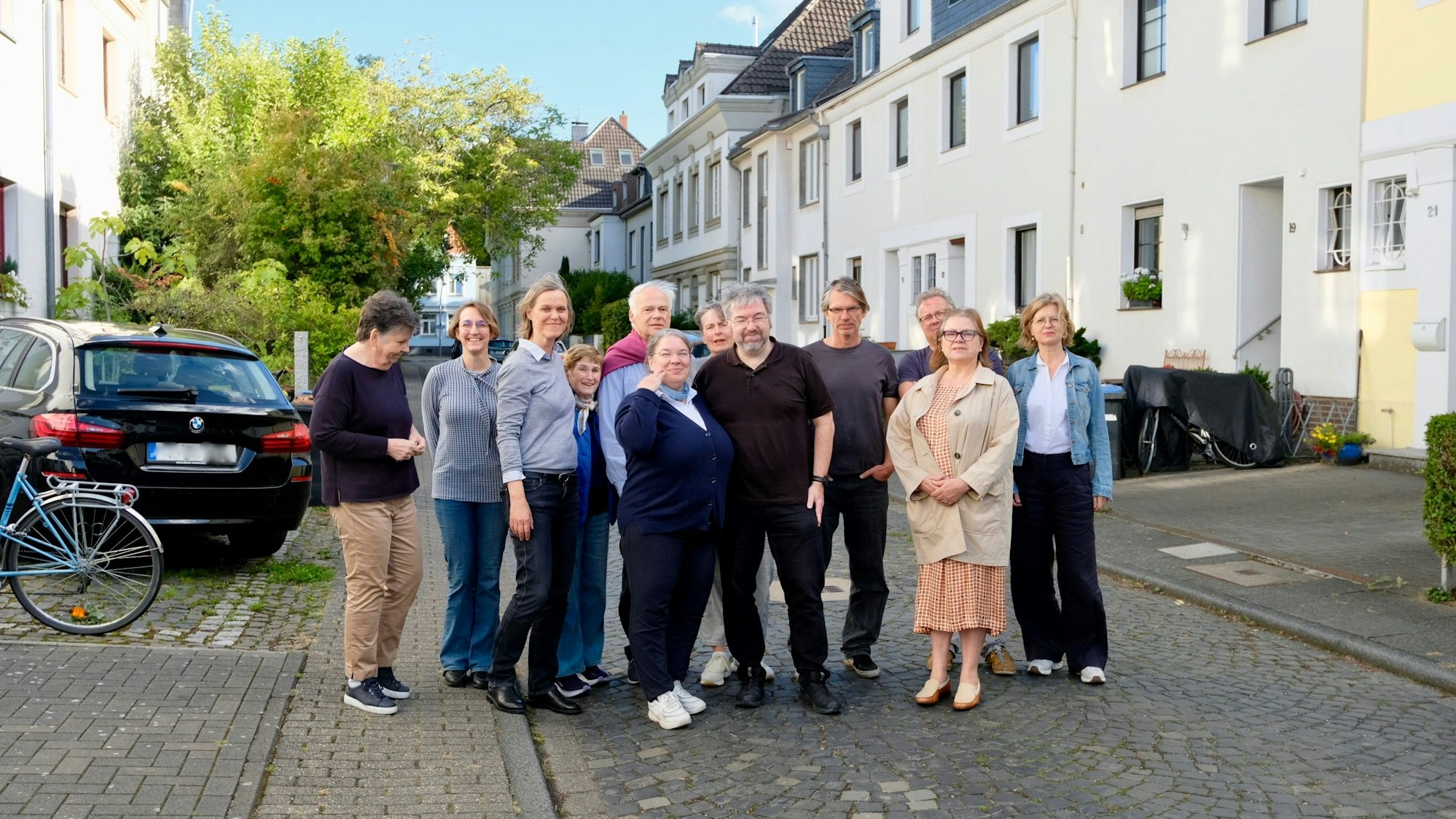 Anwohner und Anwohnerinnen der Sielsdorfer Straße stehen als Gruppe versammelt auf der Straße.