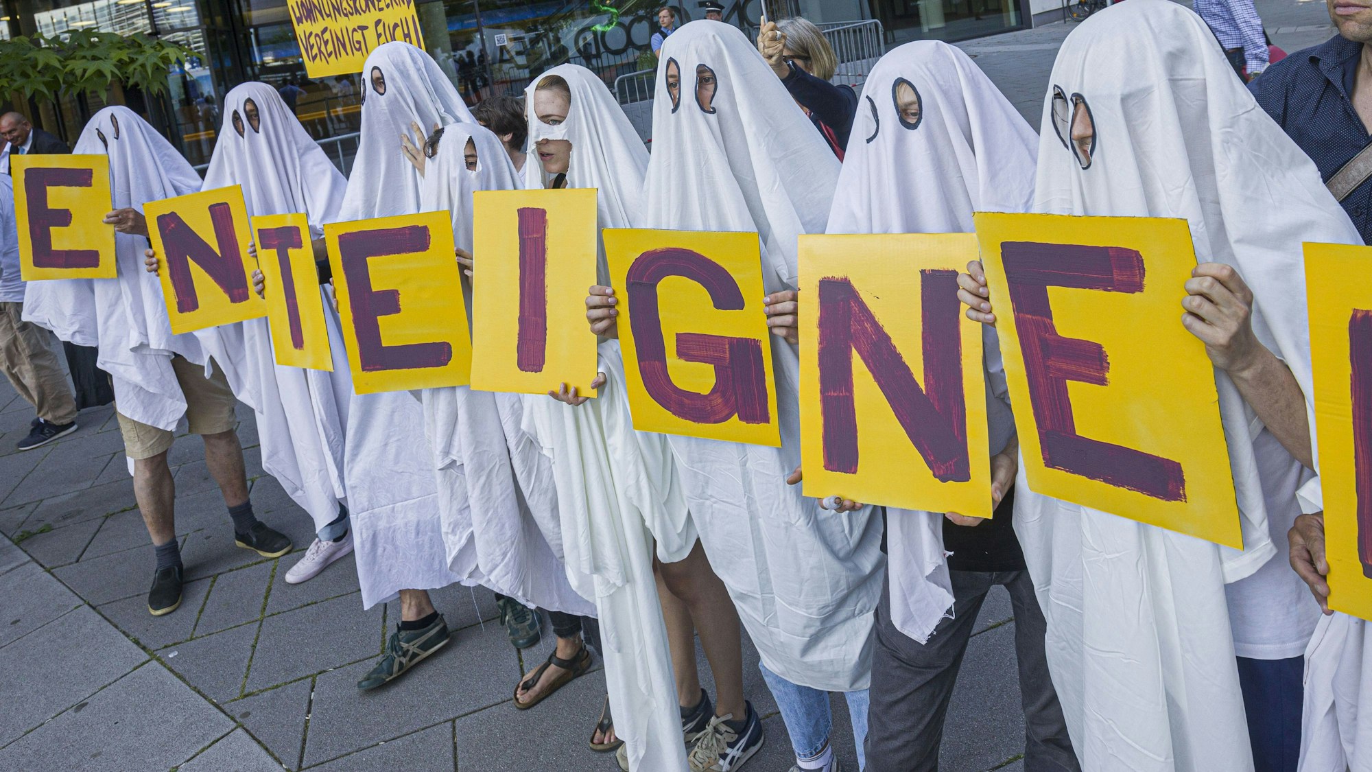 Als Geister verkleidete Demonstranten stehen am Morgen vor dem Eingang zur Hauptversammlung des Immobilienkonzerns Deutsche Wohnen und halten Buchstaben mit der Forderung "Enteignen". +++ dpa-Bildfunk +++