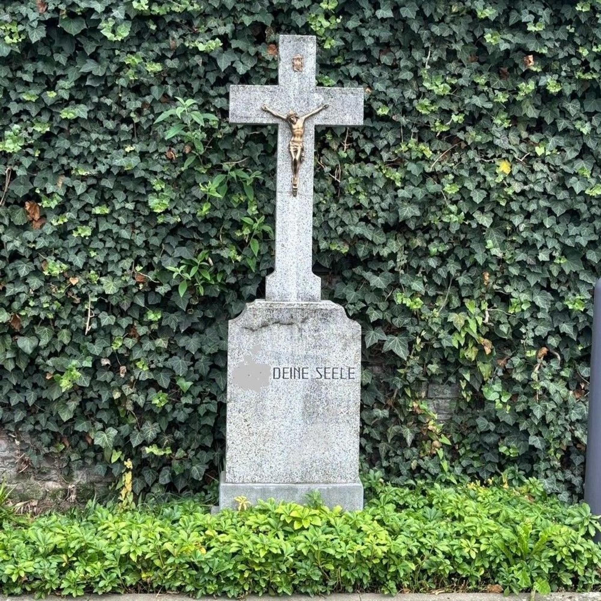 Auf dem Bild ist ein altes Steinkreuz mit einer Inschrift zu sehen.