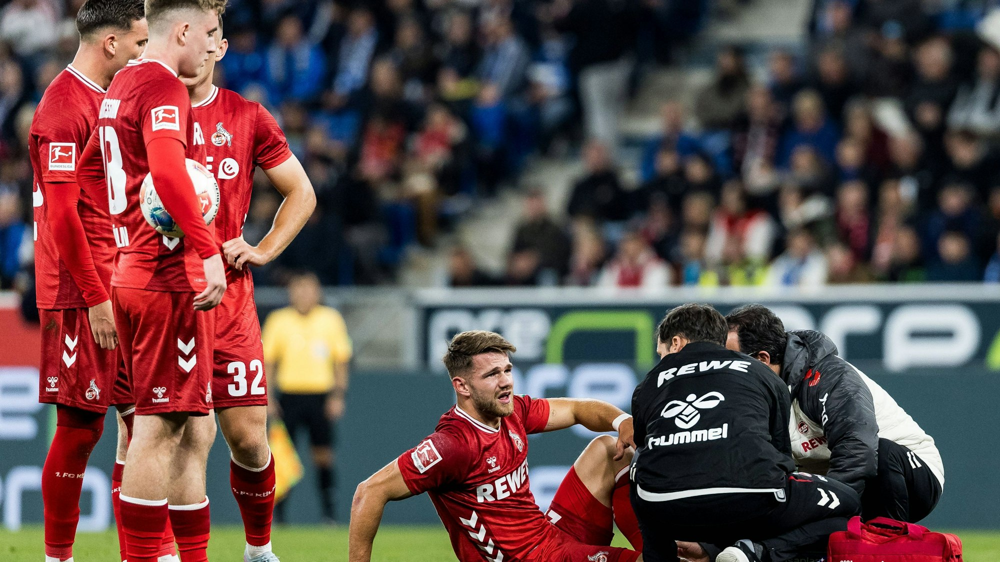 Jan Thielmann wird auf dem Spielfeld behandelt, seine Mitspieler stehen daneben und schauen zu.