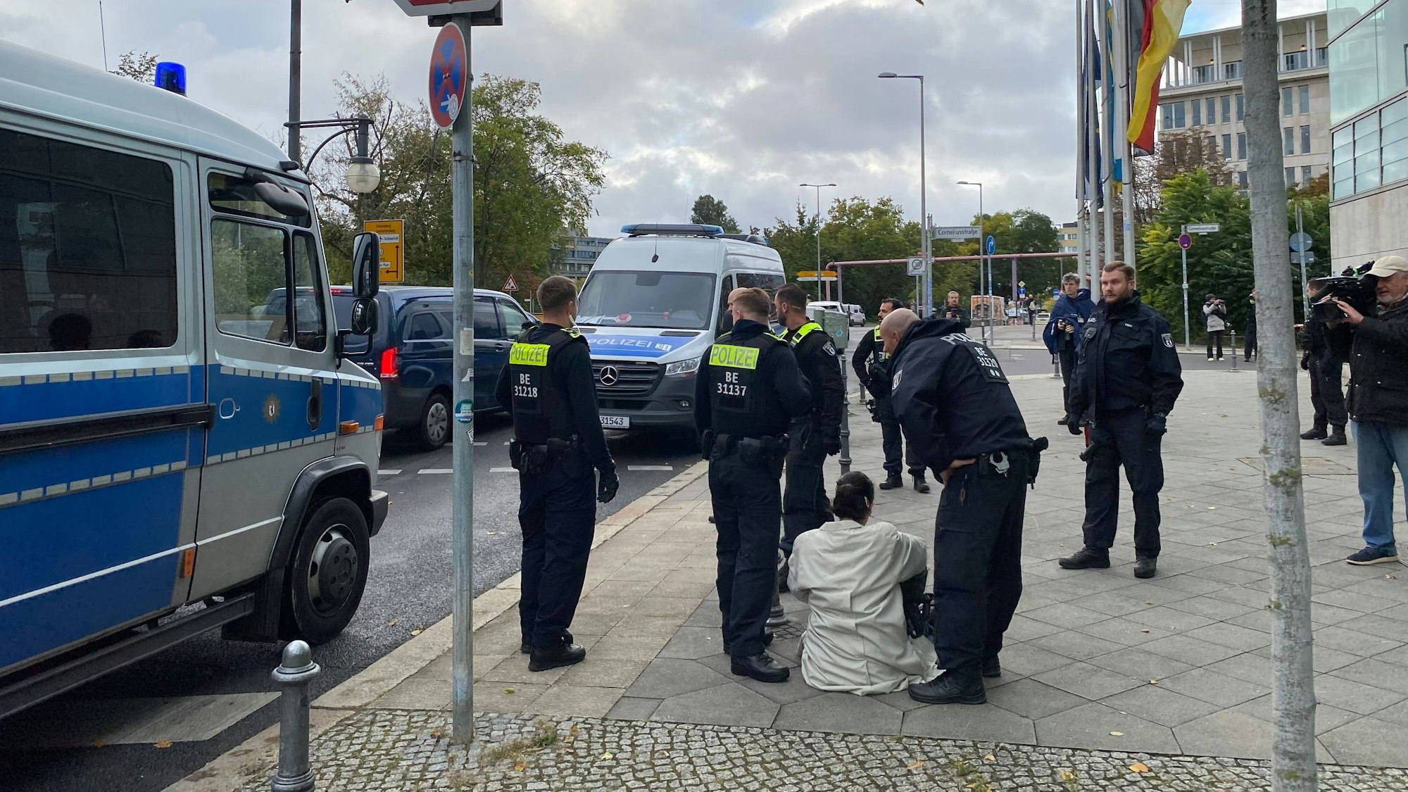 Polizisten sprechen mit einer Person, die am Boden vor der CDU-Bundeszentrale sitzt.