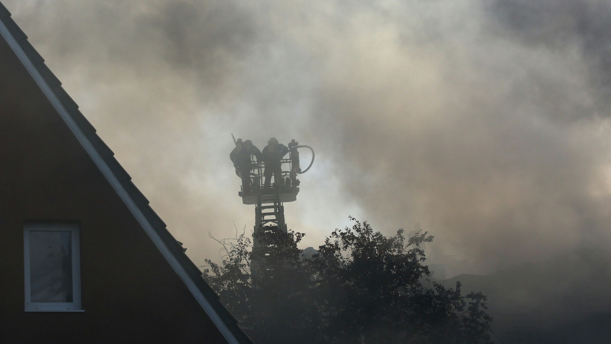 Feuerwehrleute stehen in einem Feuerwehrkran im Rauch (Symbolfoto).