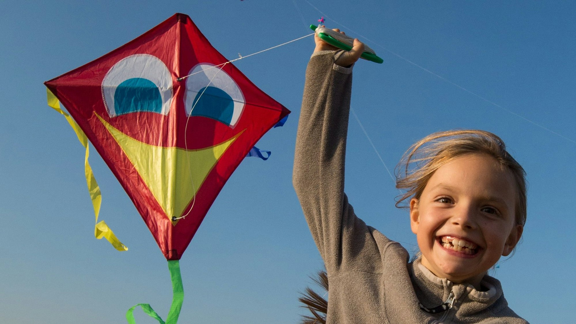 Ein Mädchen rennt mit ihrem Drachen. (Symbolbild)