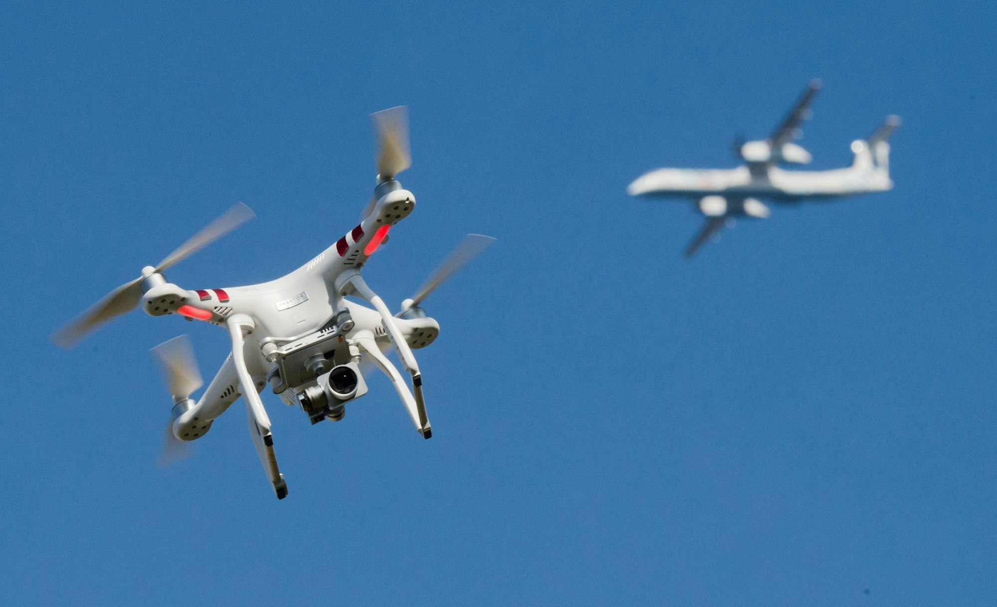 Eine private Drohne fliegt in weiter Entfernung von einem Flugzeug, das im Anflug auf den Flughafen Düsseldorf ist. (Symbolbild)