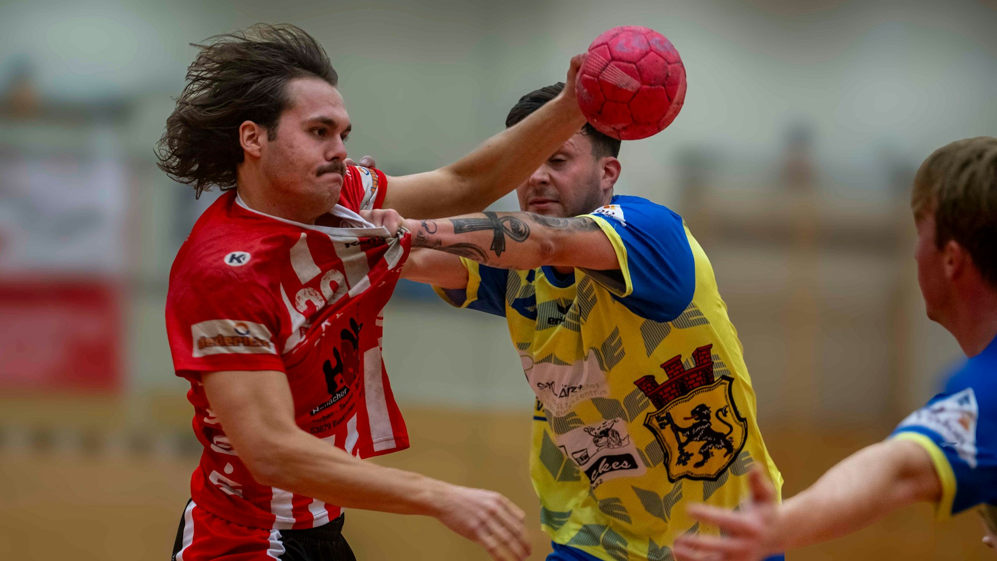 Jarl Schramm blickt entschlossen drein, obwohl ihm ein Gegner am Kragen des Trikots zieht.