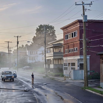 Ein Mann betrachtet einen auf die Straße gestürzten Laternenpfahl.