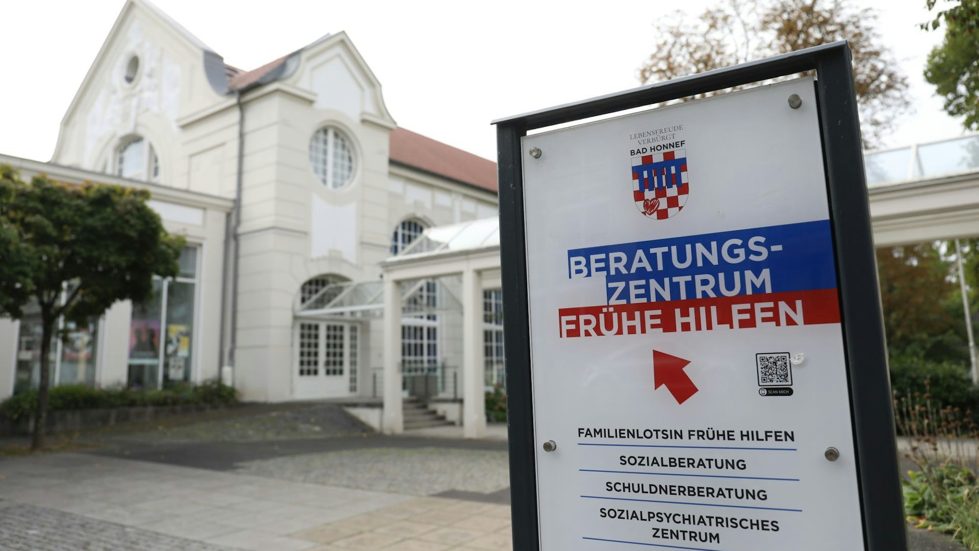 Ein Schild mit den Angeboten des Beratungszentrums Frühe Hilfe, im Hintergrund ein historisches Jugendstilgebäude.