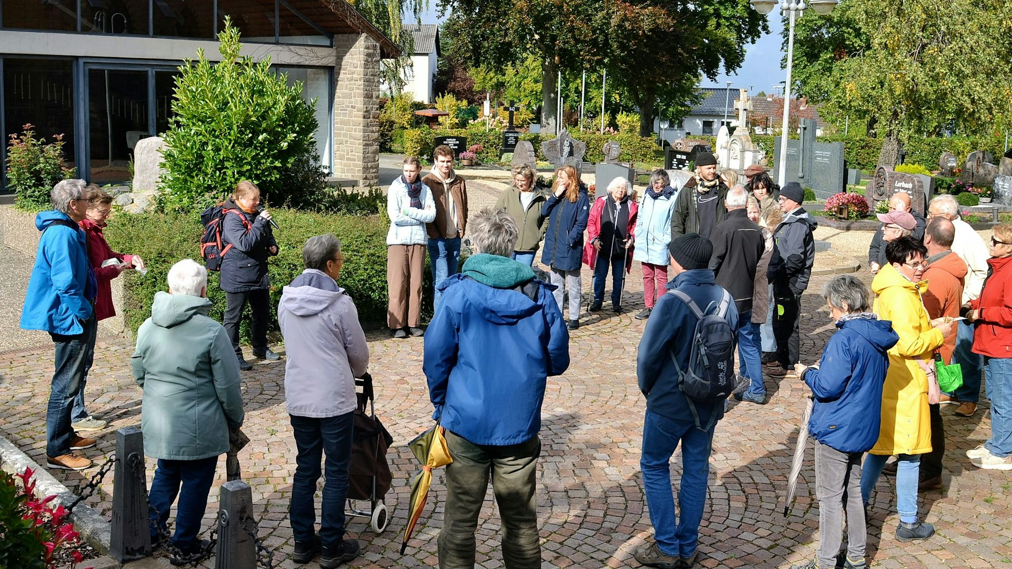 Eine Menschengruppe steht im Kreis angeordnet auf Pflastersteinen.