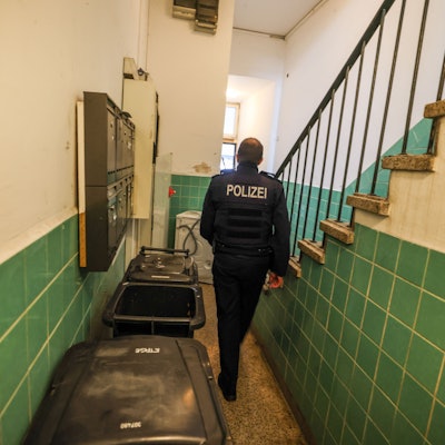 Ein Polizeibeamter geht in Hagen durch ein Treppenhaus bei einer Kontrolle im Kampf gegen kriminelle Geschäftsmodelle mit Schrottimmobilien und Sozialbetrug.