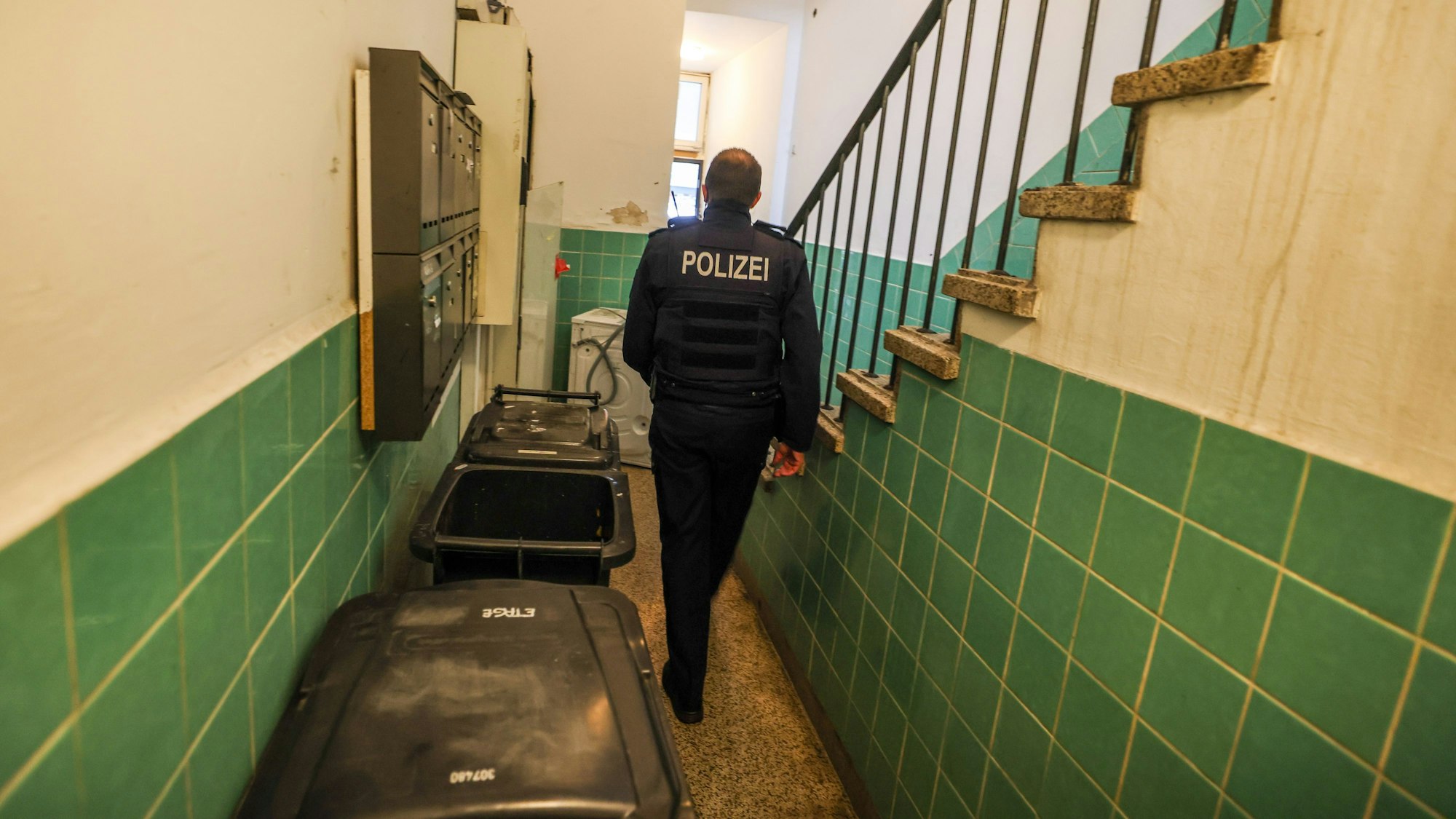 Ein Polizeibeamter geht in Hagen durch ein Treppenhaus bei einer Kontrolle im Kampf gegen kriminelle Geschäftsmodelle mit Schrottimmobilien und Sozialbetrug.
