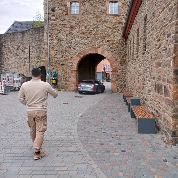 Ein Auto fährt durch das Orchheimer Tor in Bad Münstereifel, ein Fußgänger betritt den verkehrsberuhigten Bereich davor.