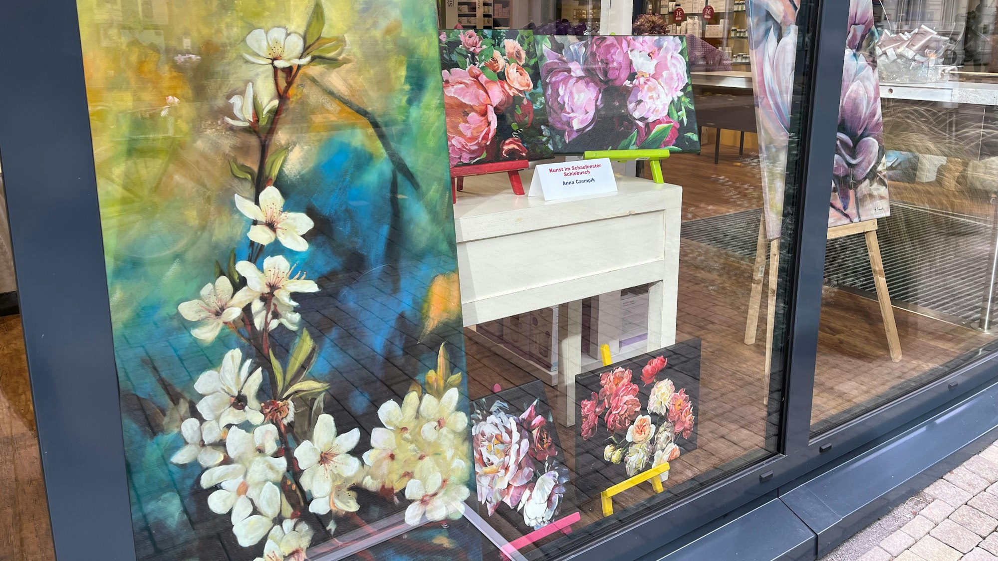 Ein gemaltes Bild steht in einem Schaufenster.