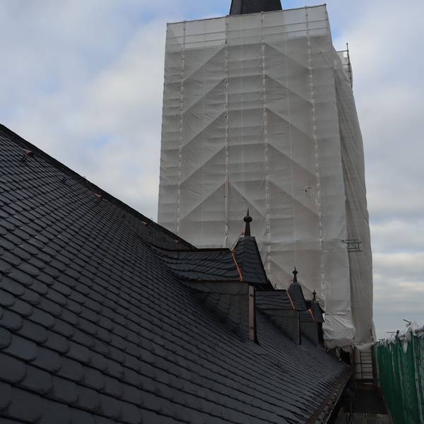 Zu sehen ist ein Kirchturm, der in ein Schutznetz gehüllt ist.