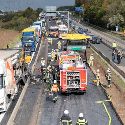 Einsatzkräfte der Feuerwehr und der Polizei sind an der Unfallstelle, nachdem zwischen der Anschlussstelle Wahn und Lind auf der A59 mehrere Fahrzeuge kollidiert sind. Ein Pkw ist laut Polizei in Flammen aufgegangen. Nach ersten Erkenntnissen ist der Pkw auf ein Wohnmobil aufgefahren, im Anschluss soll ein Lkw in die Unfallstelle gefahren sein. Foto: Thomas Banneyer/dpa