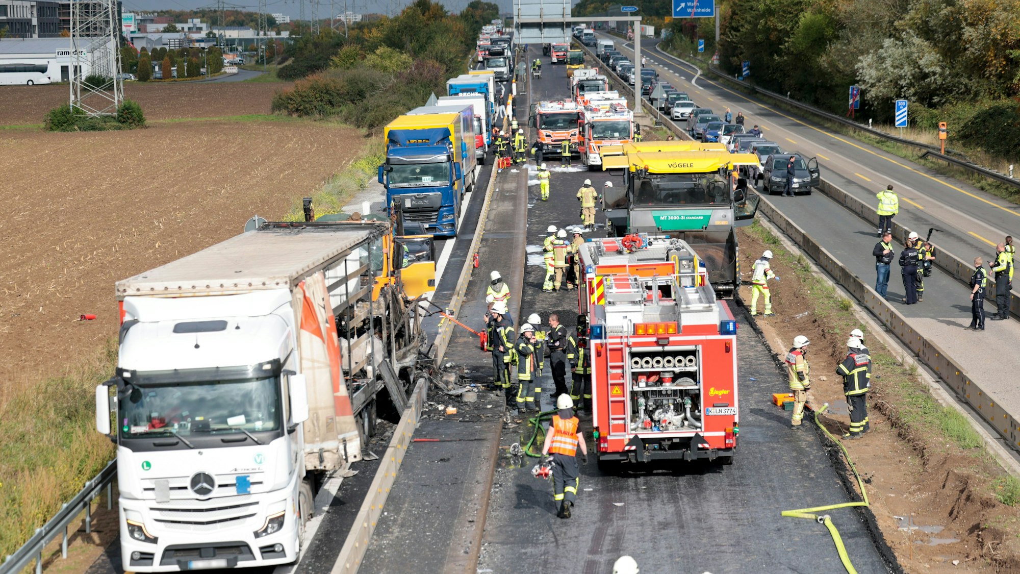 Einsatzkräfte der Feuerwehr und der Polizei sind an der Unfallstelle, nachdem zwischen der Anschlussstelle Wahn und Lind auf der A59 mehrere Fahrzeuge kollidiert sind. Ein Pkw ist laut Polizei in Flammen aufgegangen. Nach ersten Erkenntnissen ist der Pkw auf ein Wohnmobil aufgefahren, im Anschluss soll ein Lkw in die Unfallstelle gefahren sein. Foto: Thomas Banneyer/dpa