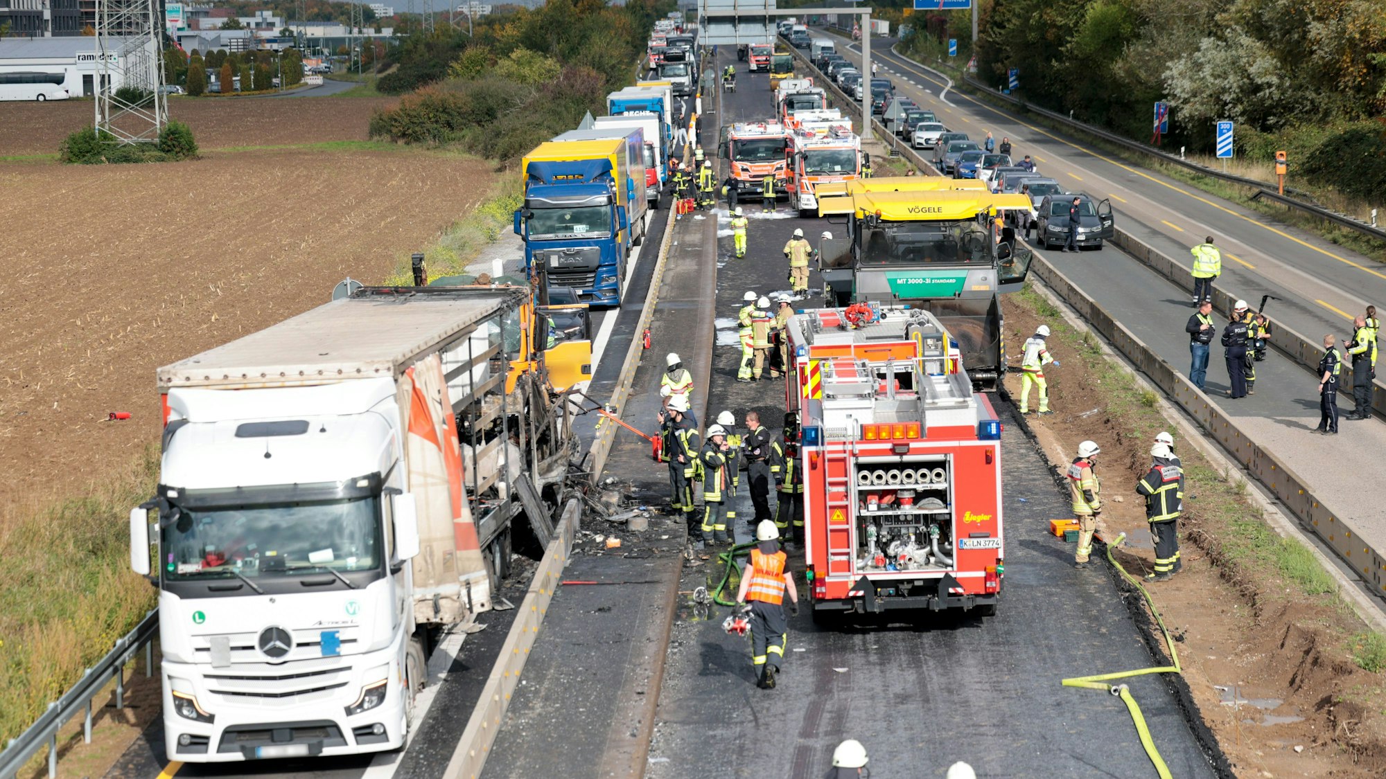 Das Bild zeigt Einsatzkräfte der Feuerwehr und der Polizei an der Unfallstelle, nachdem zwischen der Anschlussstelle Wahn und Lind auf der A59 mehrere Fahrzeuge kollidiert sind. Foto: Thomas Banneyer/dpa