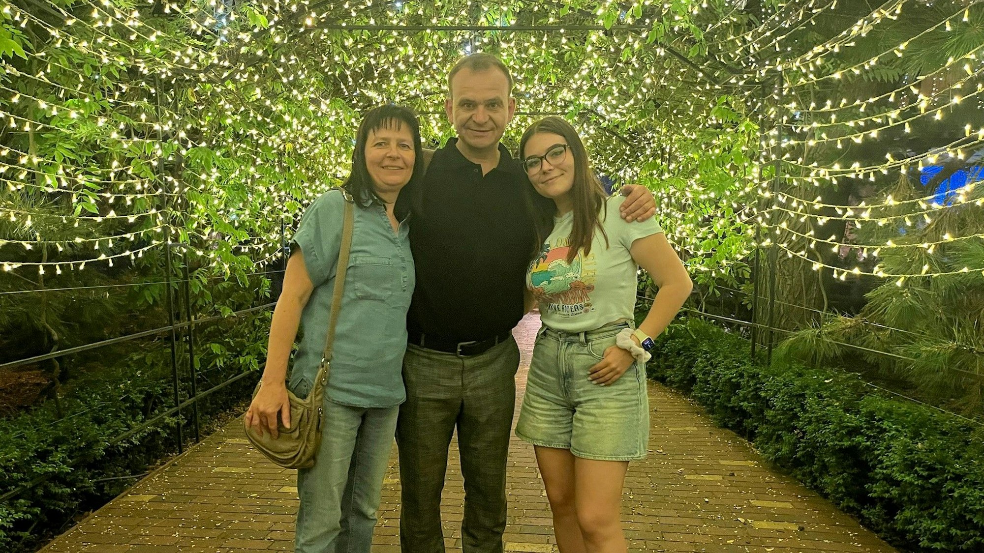 Die Familie steht dicht beisammen, über ihnen zahlreiche Lichterketten.