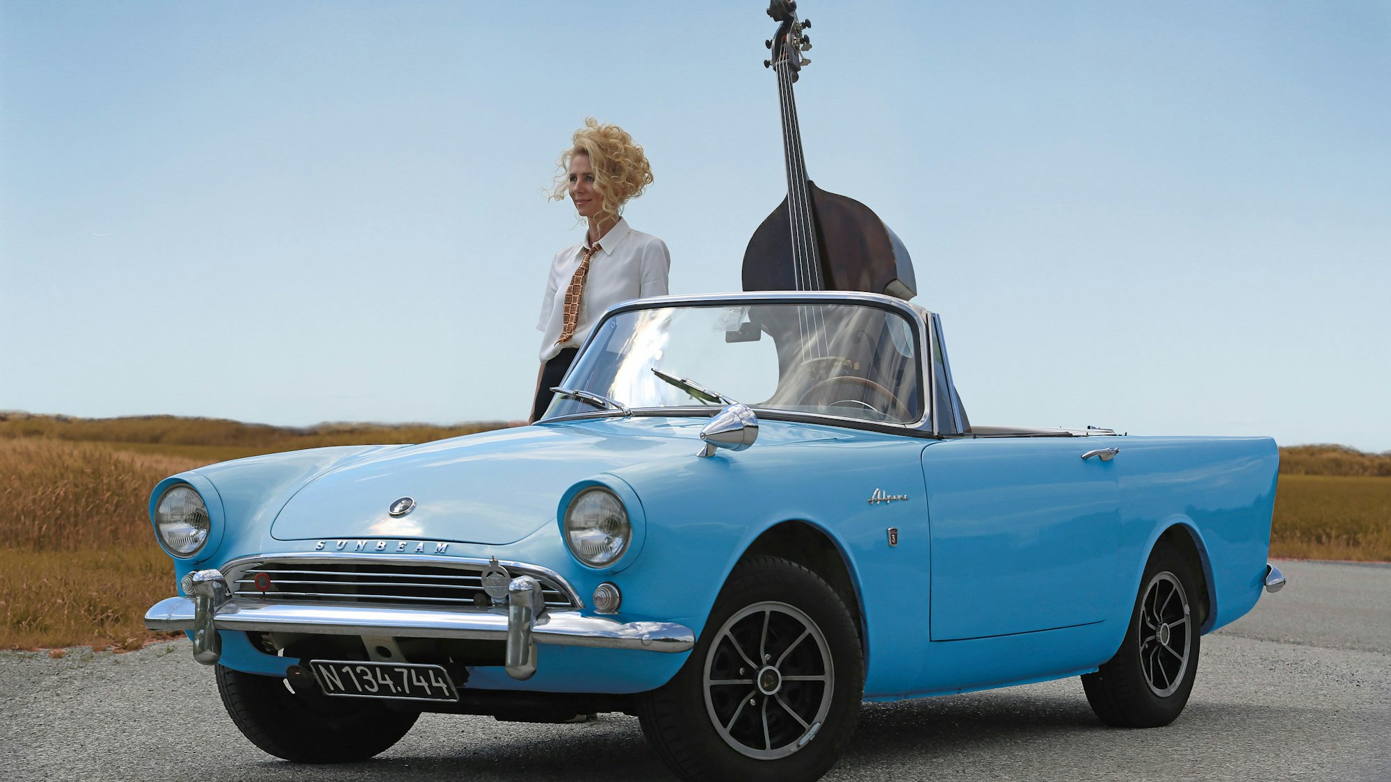 Gina Schwarz nebst Instrument in einem babyblauen Auto