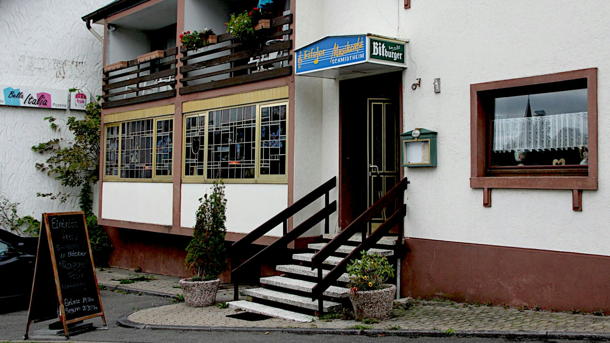 Eine Außenansicht, des „Eifeler Musikcafés“ in Schmidtheim, davor steht eine Klapptafel, auf der für das nächste Event geworben wird.