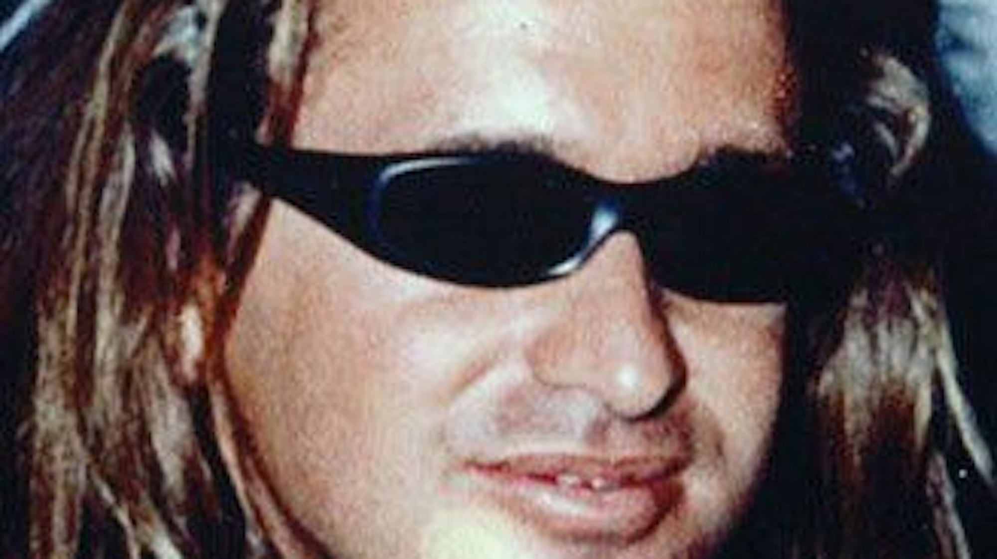 Ein Mann mit langen Haaren trägt eine Sonnenbrille.