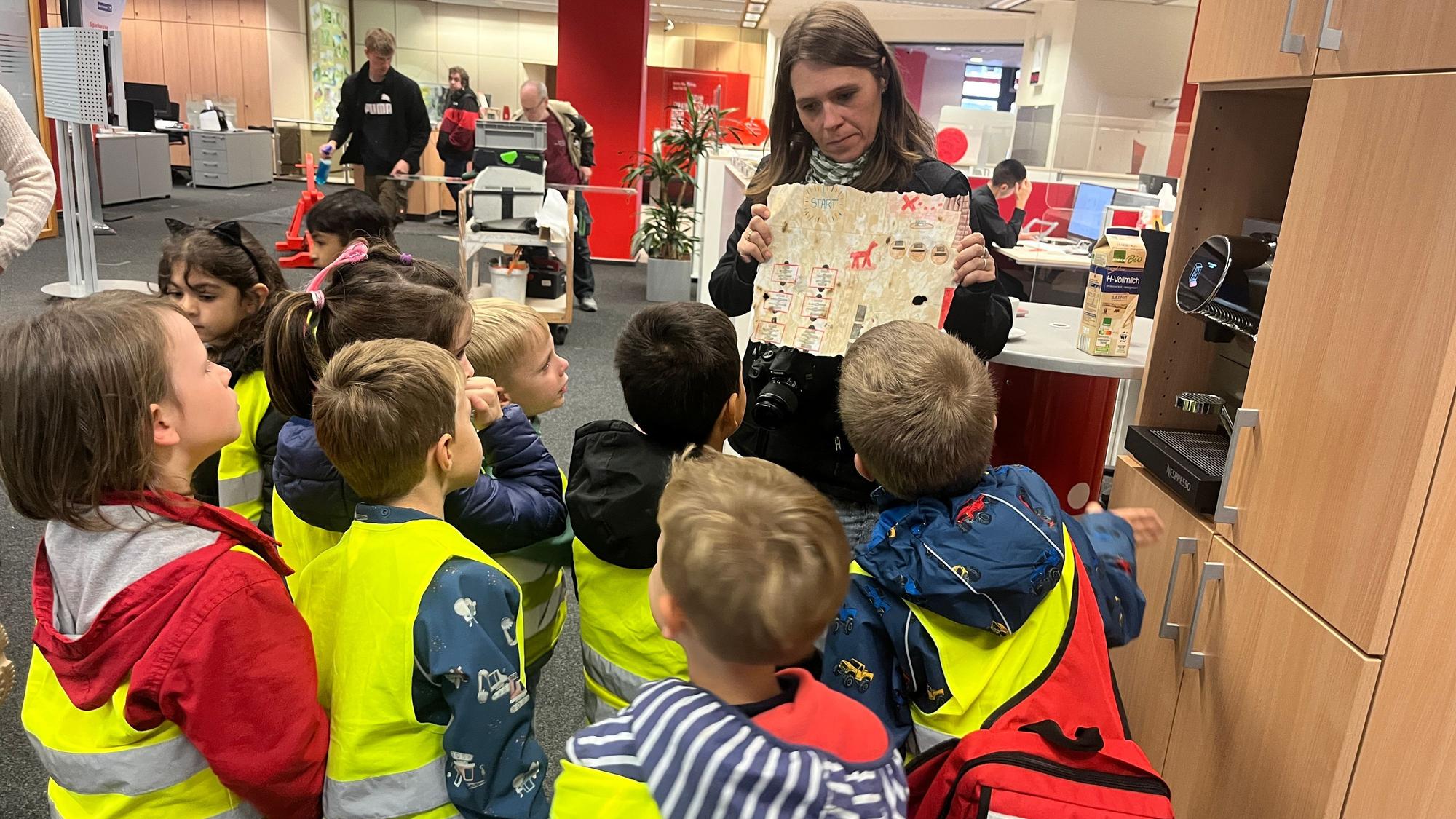 Die Adlergruppe des katholischen Kindergartens St. Patricius besuchte die Kreissparkasse in Eitorf, Erzieherin Jenny Schwarz zeigt die Schatzkarte.