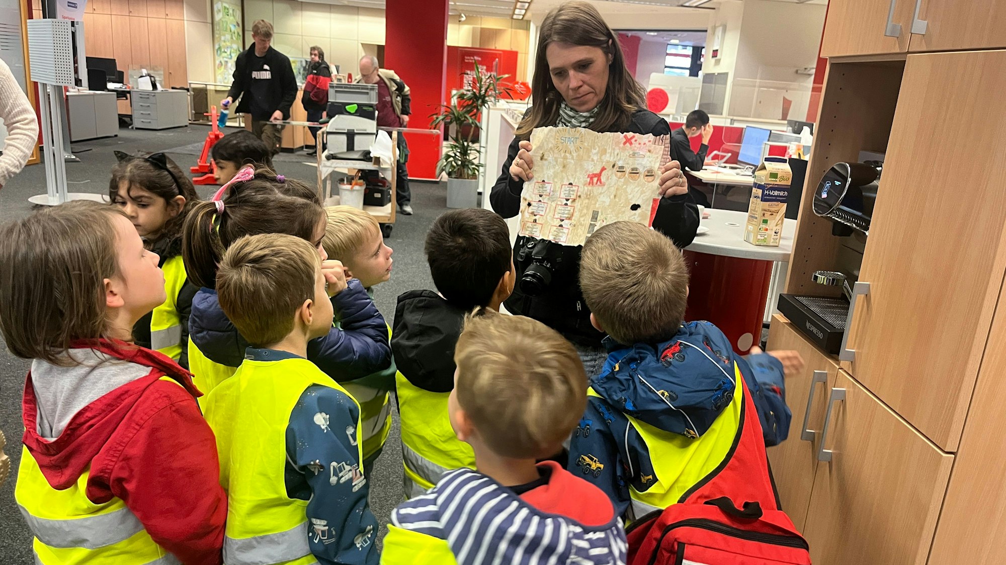 Die Adlergruppe des katholischen Kindergartens St. Patricius besuchte die Kreissparkasse in Eitorf, Erzieherin Jenny Schwarz zeigt die Schatzkarte.