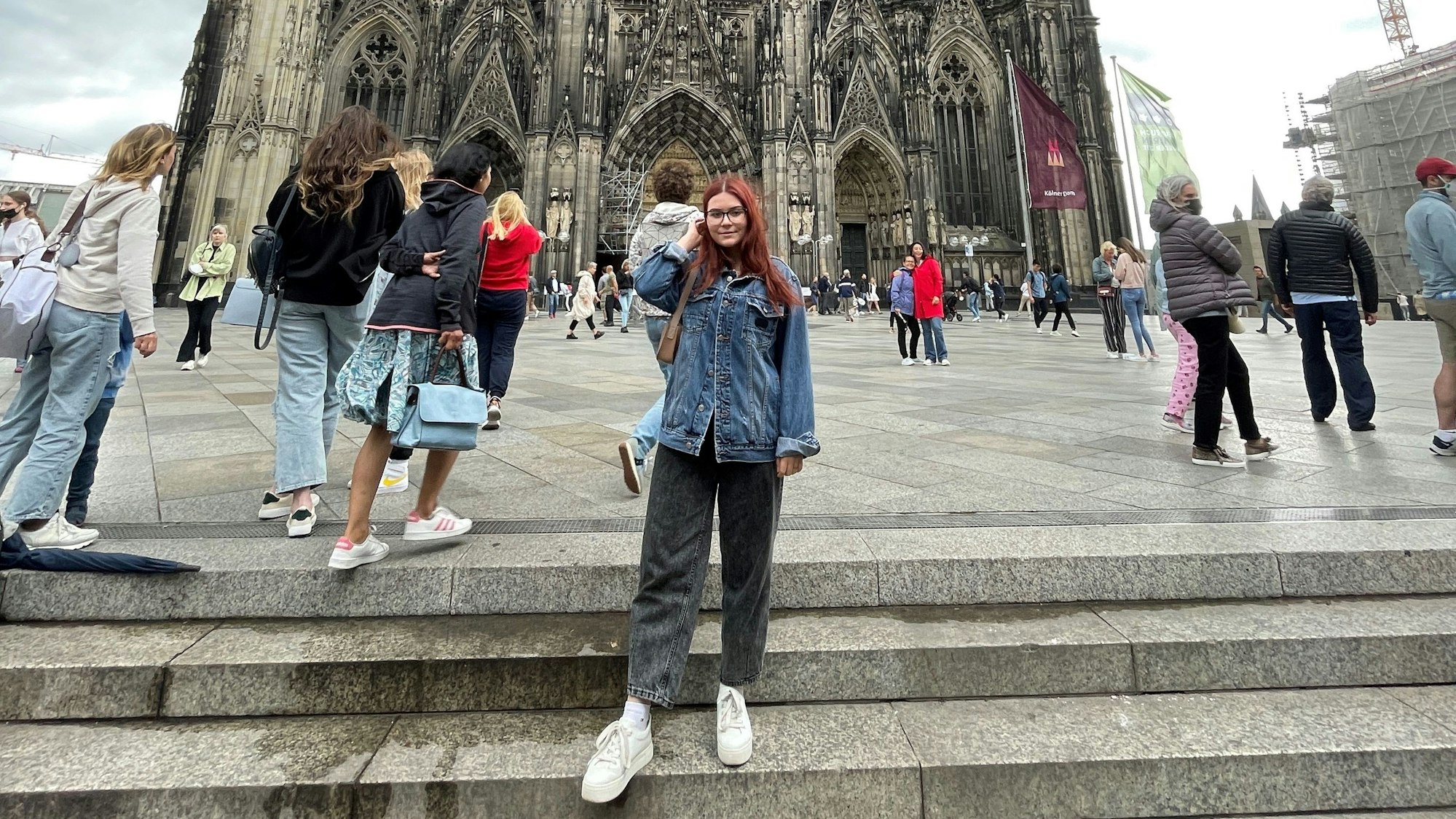 Yuliia Radhenko vor dem Kölner Dom. Viele Menschen sind auf der Domplatte zu sehen.