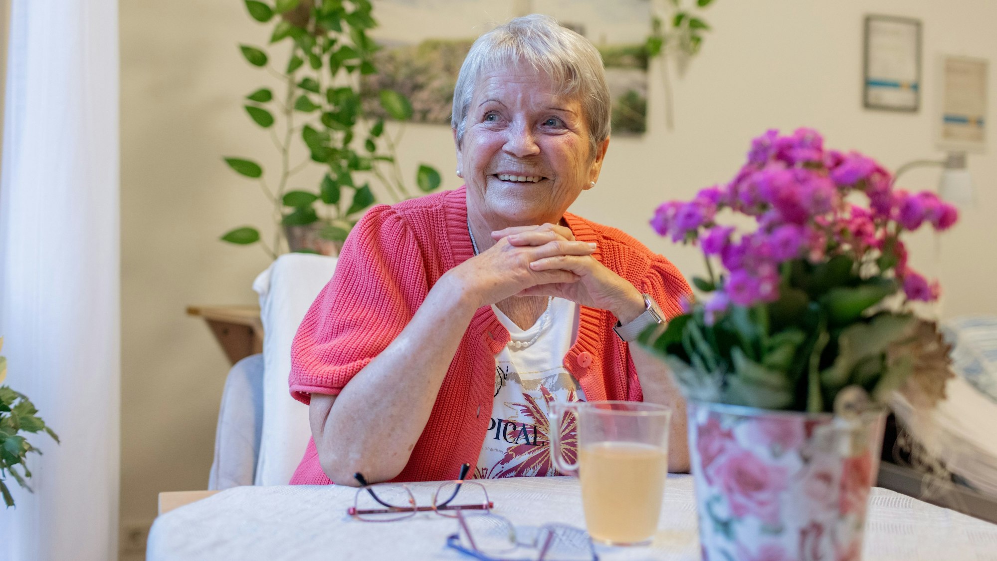06.10.2025, Süssendell: Christel Lenertz sitzt mit ineinander gefalteten Händne an einem Tisch und lächelt.