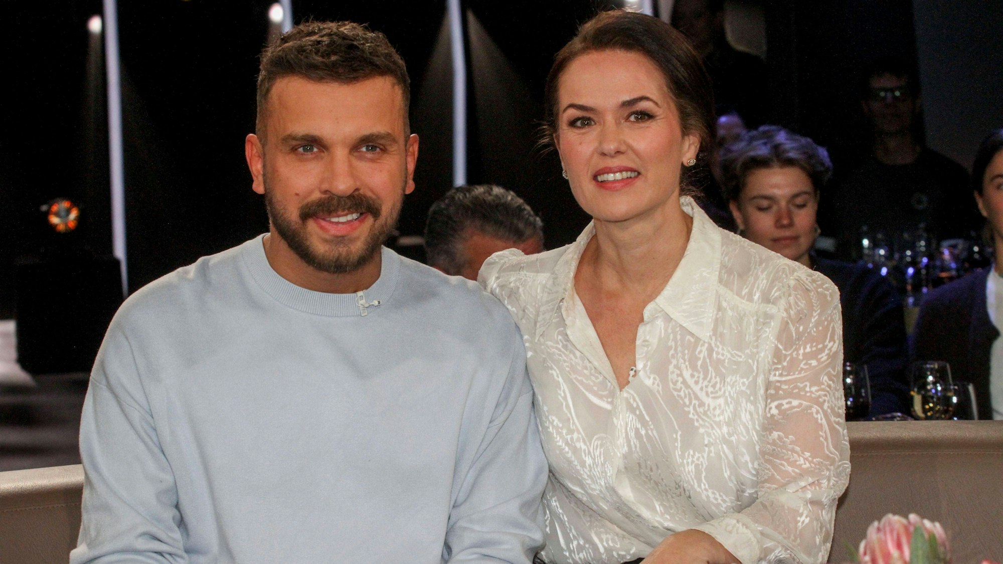 Edin Hasanović und eine Frau lächeln zusammen bei einem TV-Auftritt