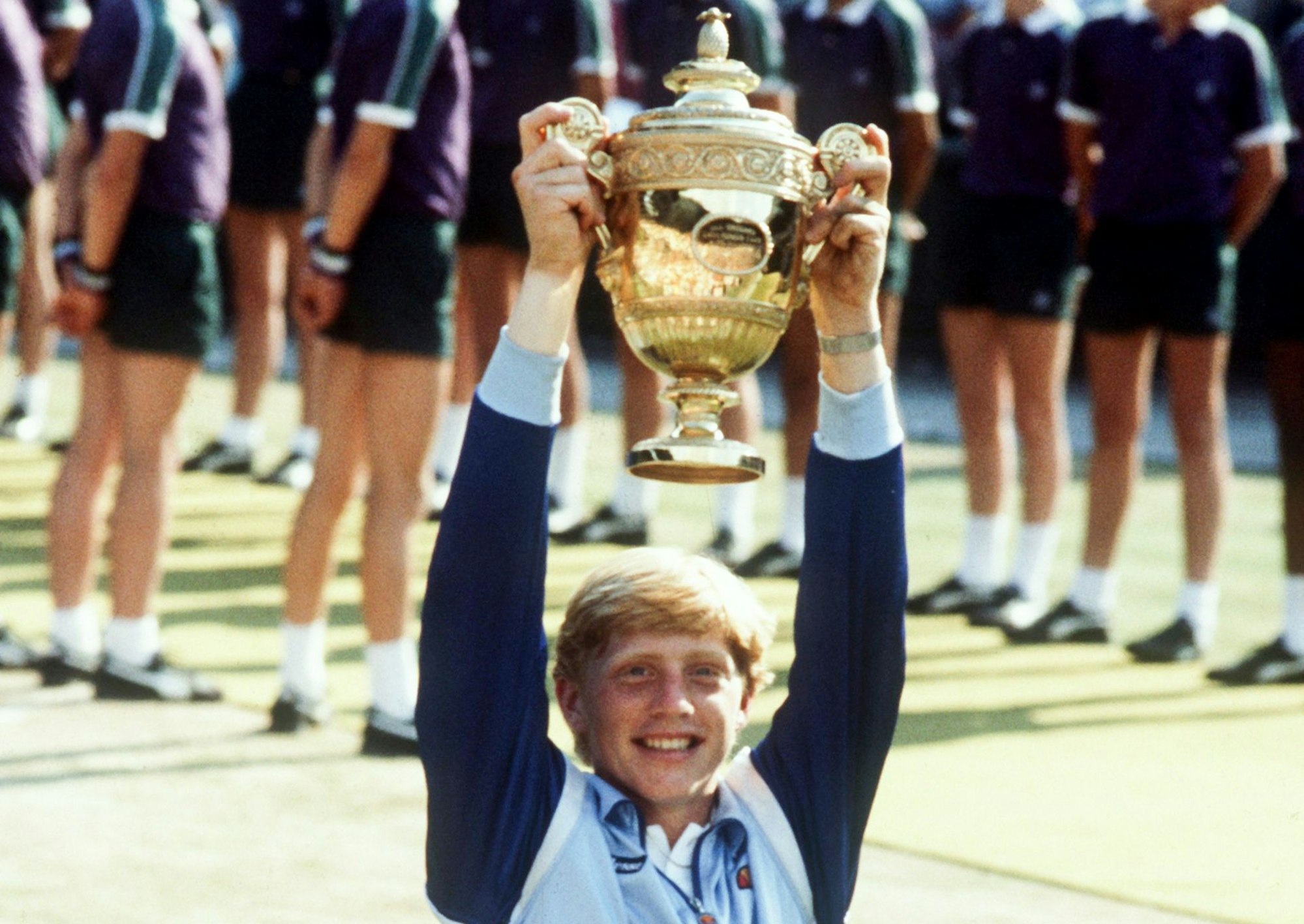 07.07.1985, Großbritannien, Wimbledon: Der erst 17-jährige deutsche Tennisspieler Boris Becker strahlt und hebt triumphierend den Siegerpokal empor, der ihm am 07.07.1985 nach seinem Erfolg über den US-Amerikaner Kevin Curren im Wimbledon-Finale überreicht worden ist.