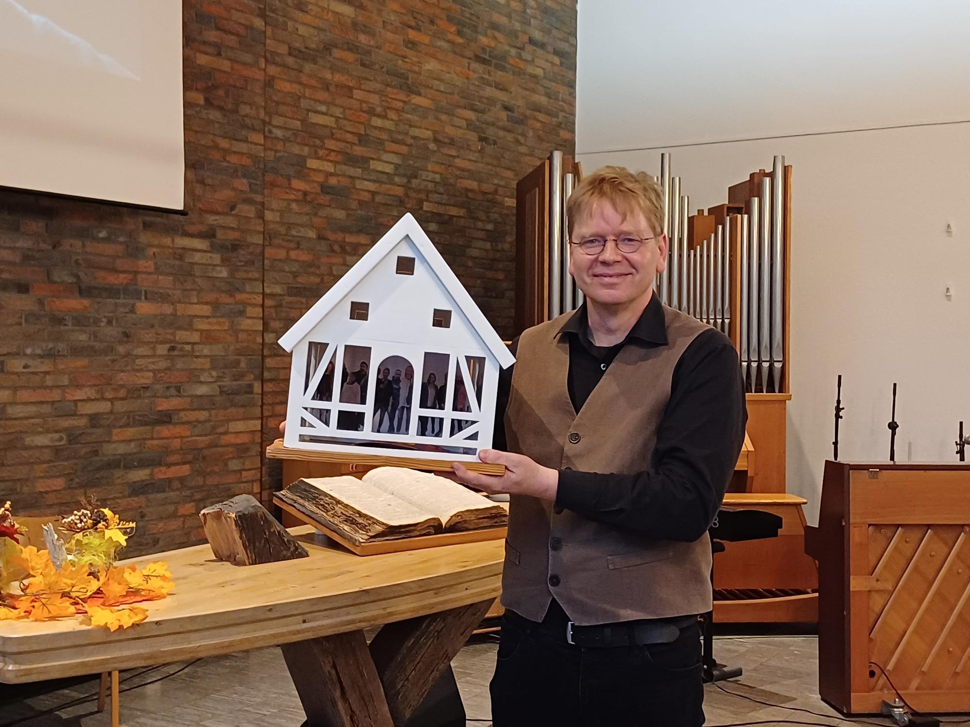 Die Caritas bedankte sich bei Pastor Scharwächter mit einem symbolischen Geschenk: einem Haus mit den Gesichtern der Wohnungslosen.