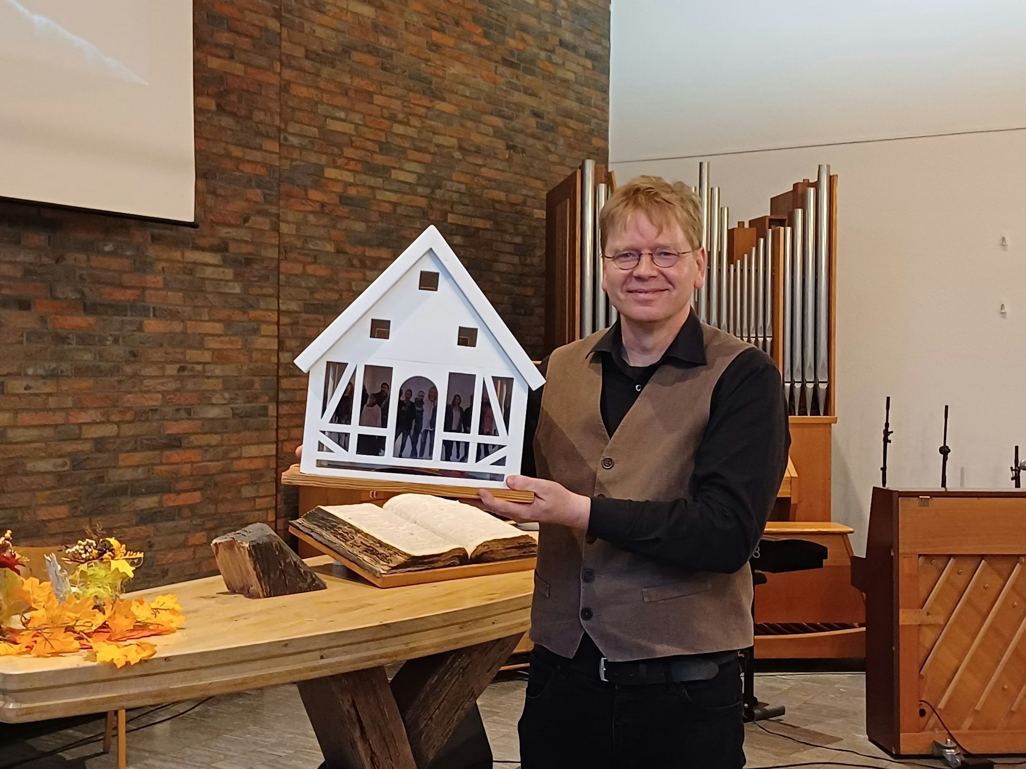 Die Caritas bedankte sich bei Pastor Scharwächter mit einem symbolischen Geschenk: einem Haus mit den Gesichtern der Wohnungslosen.