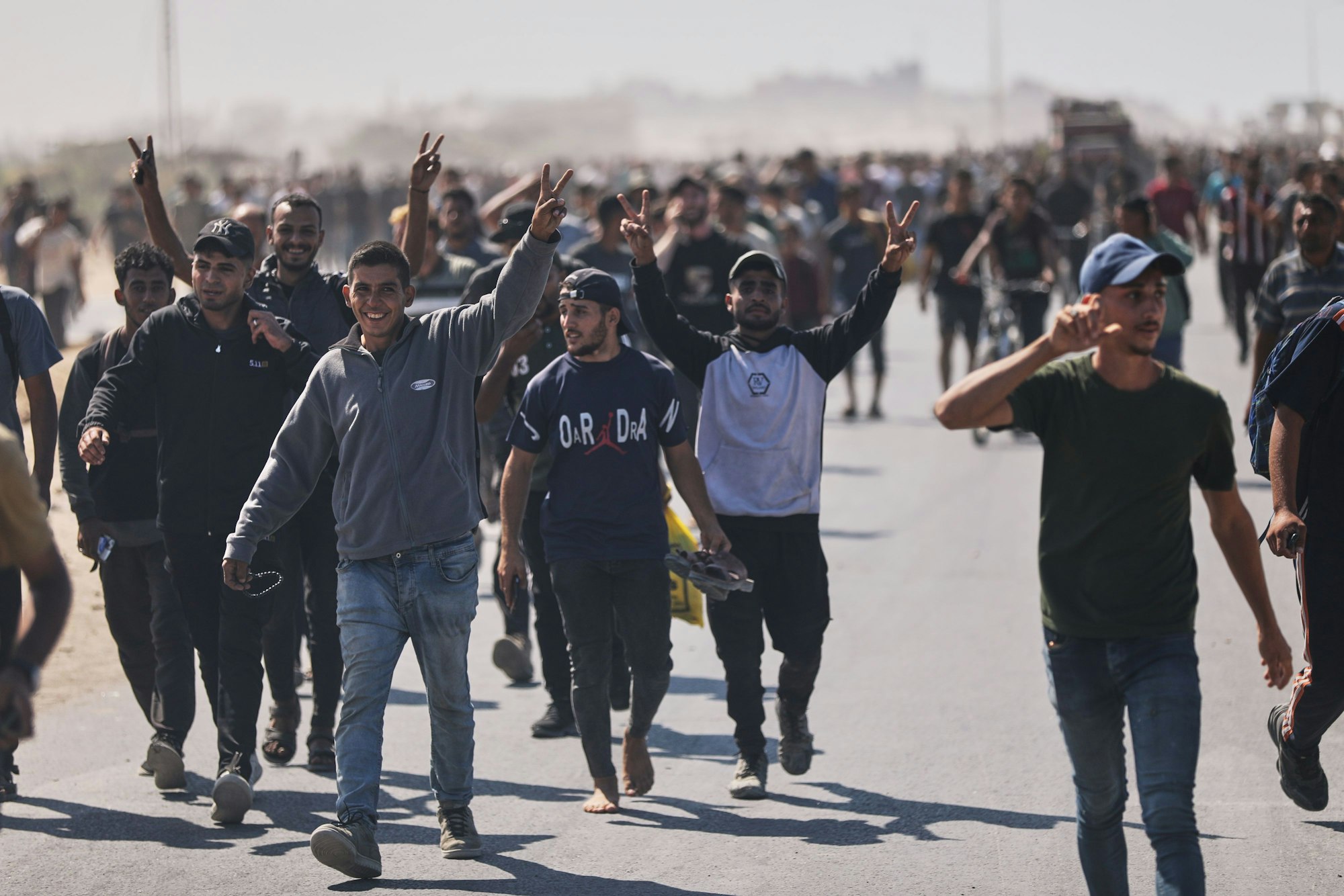 Vertriebene Palästinenser winken in die Kamera, während sie die Küstenstraße in Richtung Gaza im nördlichen Gazastreifen entlanglaufen, nachdem sich Israel und die Hamas auf eine Pause in ihrem Krieg und die Freilassung der restlichen Geiseln geeinigt haben.