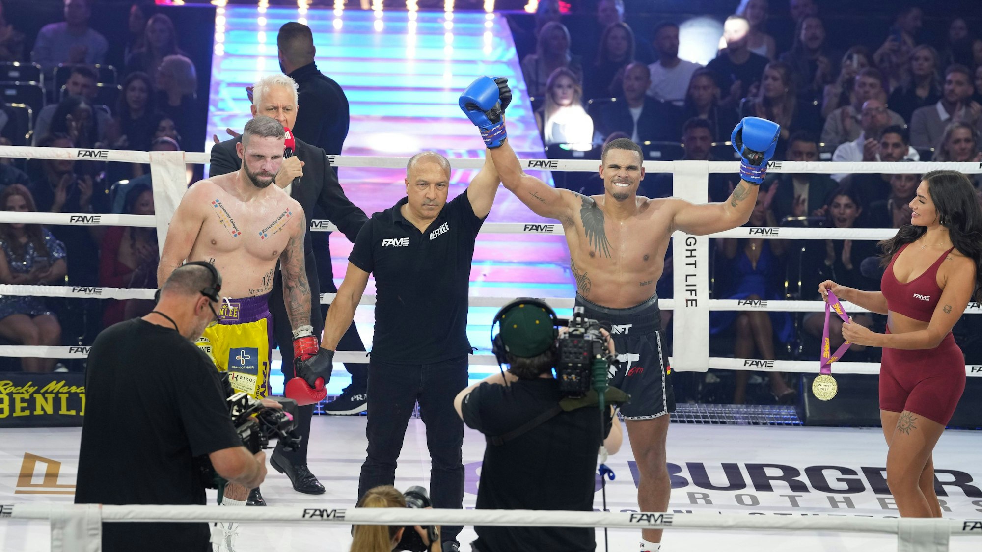 Kevin Njie feiert Sieg im Boxring, sein Arm wird vom Ringrichter gehoben.