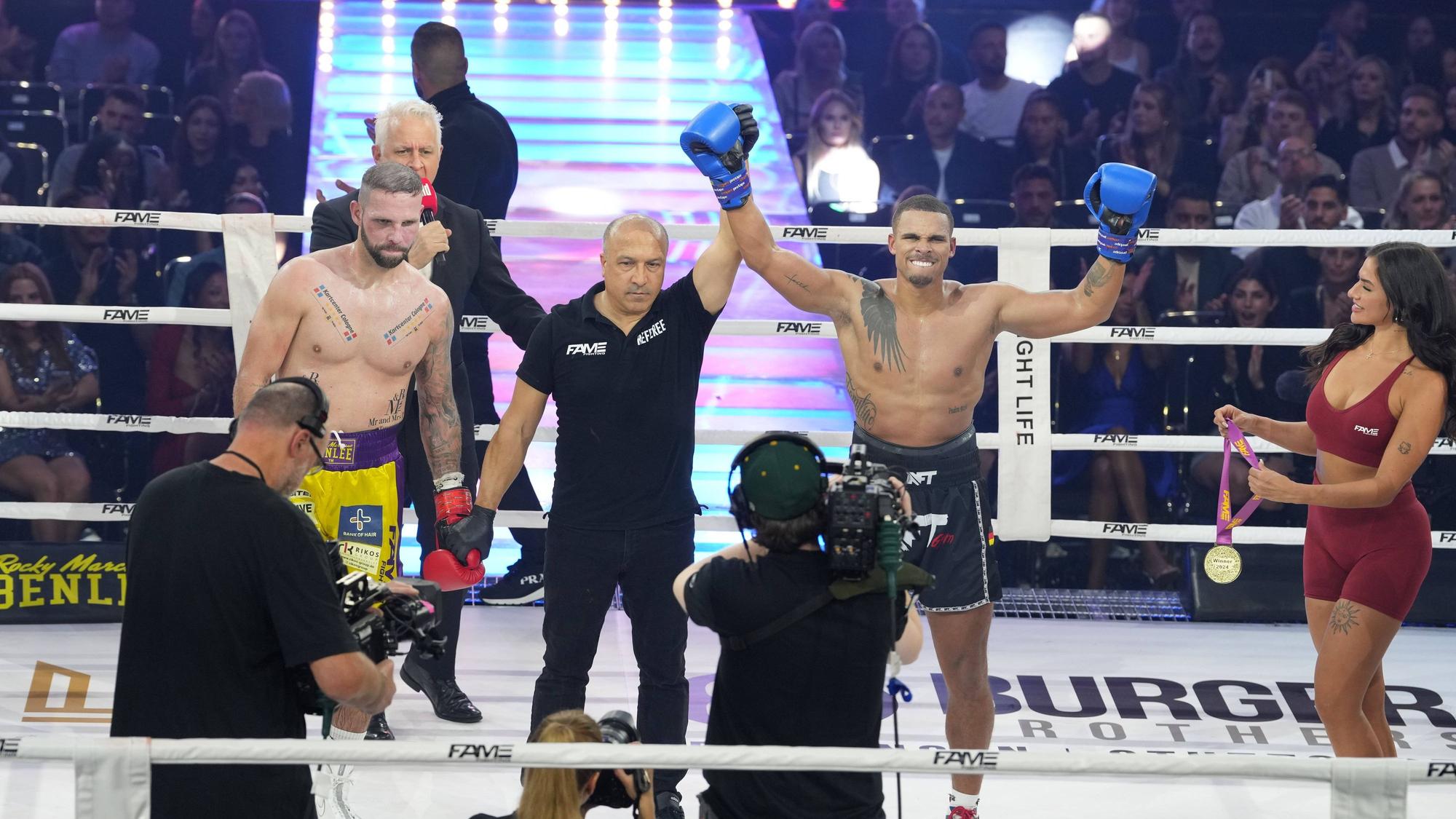 Kevin Njie feiert Sieg im Boxring, sein Arm wird vom Ringrichter gehoben
