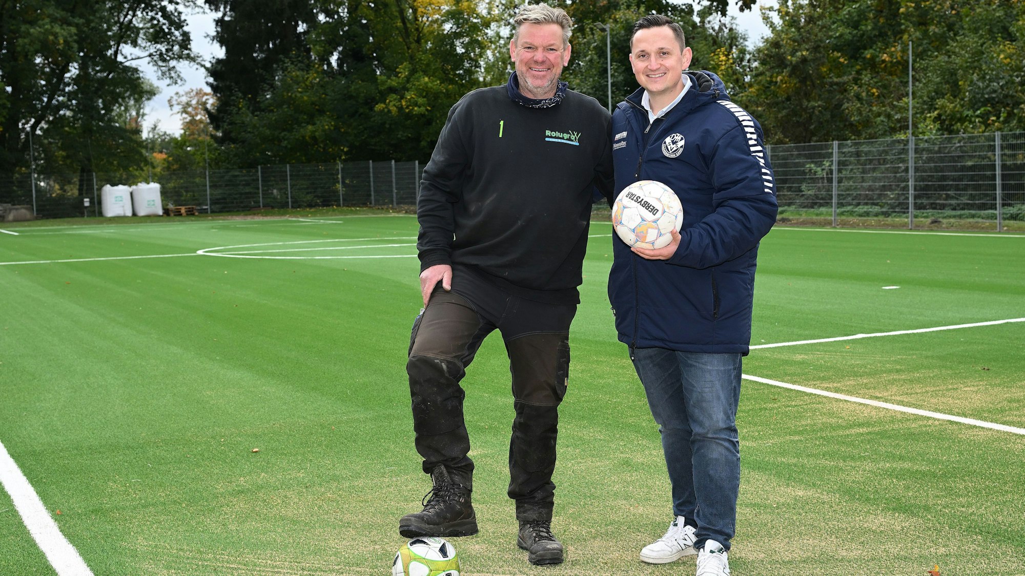 Zwei Männer stehen auf einem Fußballplatz.