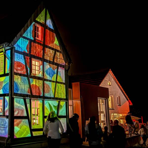 Ein Fachwerkhaus erstrahlt mit Projektionen in bunten Farben.