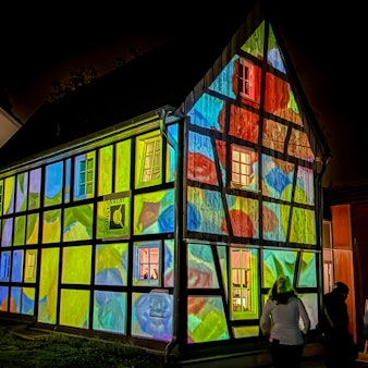 Ein Fachwerkhaus erstrahlt mit Projektionen in bunten Farben.