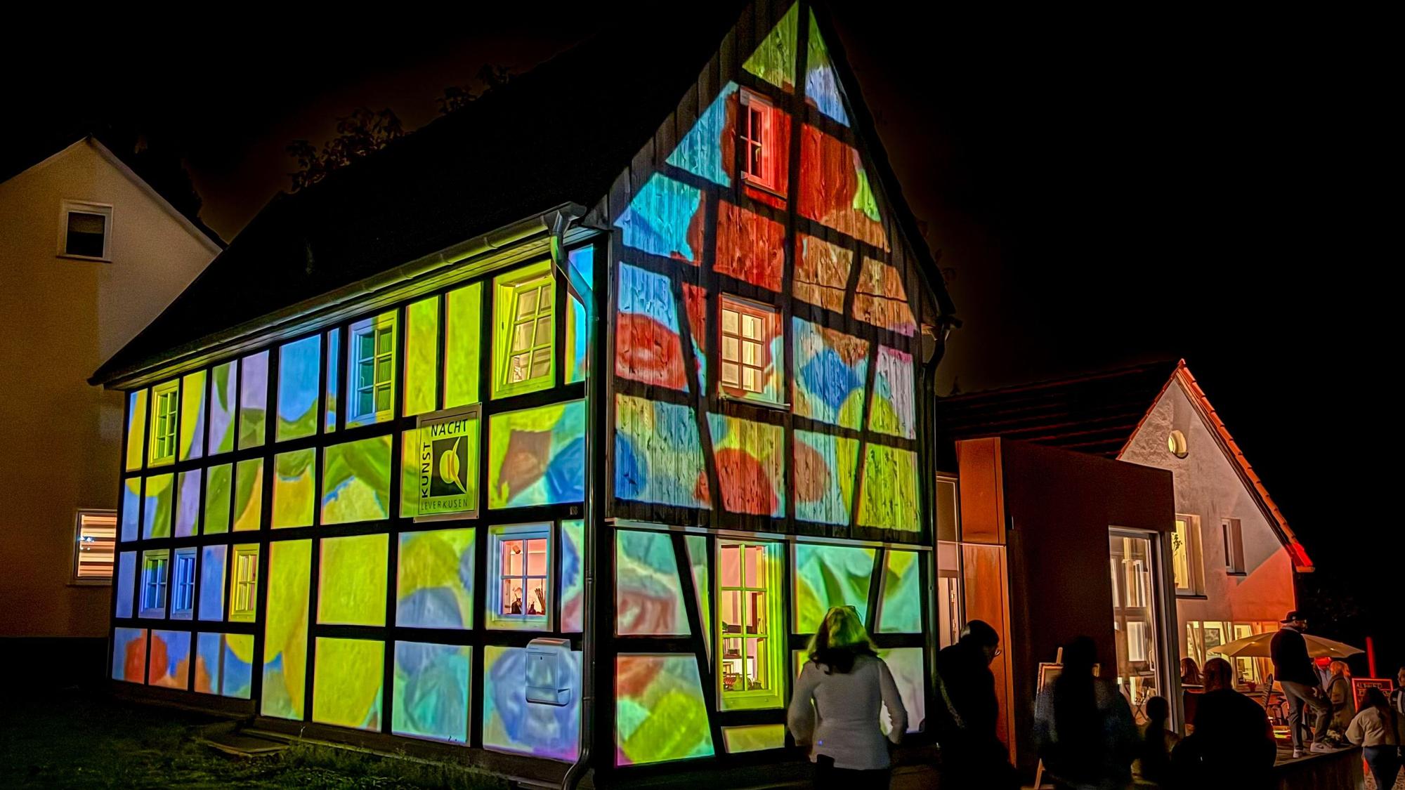 Ein Fachwerkhaus erstrahlt mit Projektionen in bunten Farben.